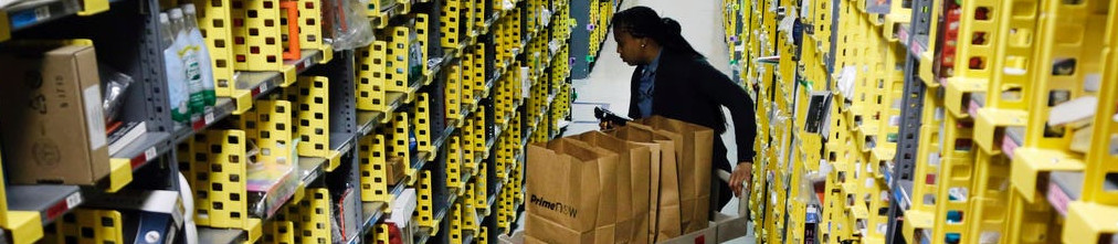Amazon employee in fulfillment center rolling trolley with paper bags