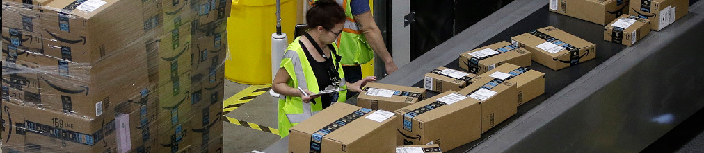 Employee sorting boxes on transporter tape of Amazon fulfillment center