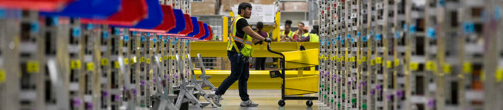 Amazon employee rolling a cart through fulfilment center