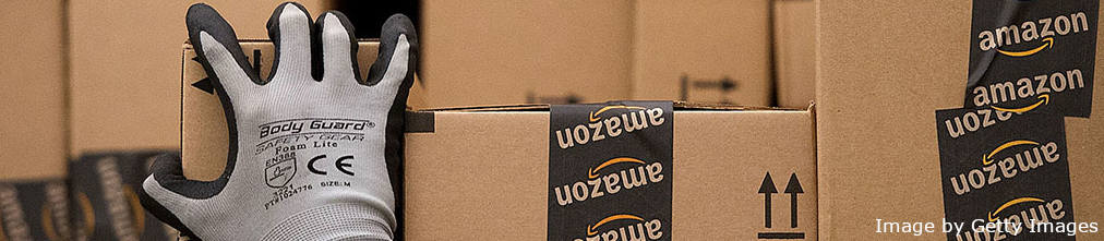 Amazon fulfillment center employee grabbing a box with Amazon.com logos on it