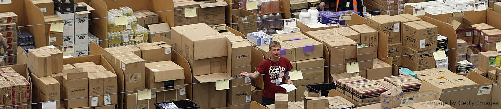 Employee surrounded by carton boxes at Amazon fulfilment center.