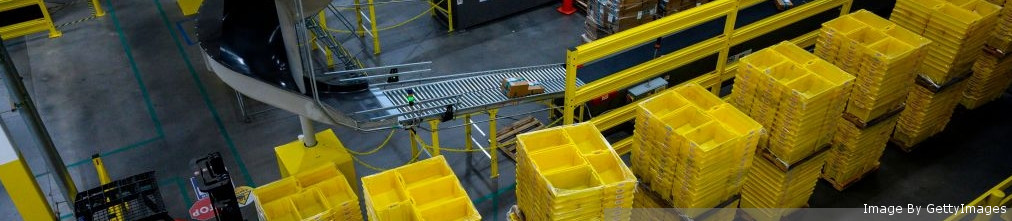 Yellow plastic boxes on transporter tape at Amazon fulfillment center