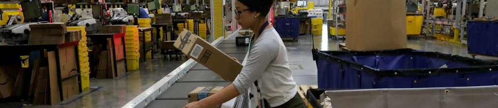Employee sorting carton boxes on conveyor tape in Amazon fulfillment center