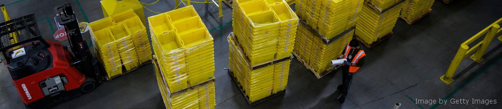 Amazon employee next to yellow boxes in fulfilment center