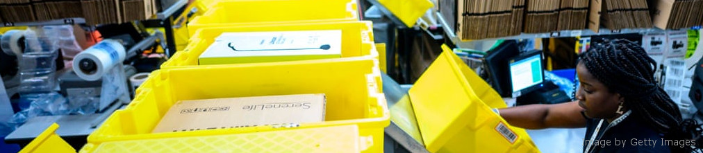 Amazon employee next to yellow boxes in fulfilment center