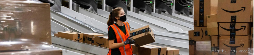 An employee carrying a cardboard box to conveyor tape in Amazon fulfillment center