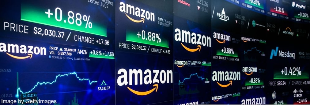 Wall of screens showing Amazon logos on blue background and rates of Amazon (AMZN) stocks