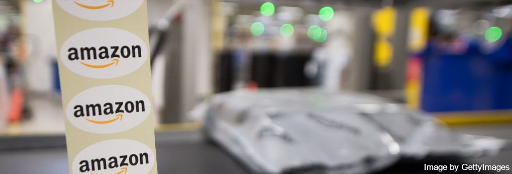 Tape with Amazon logo stickers in front and conveyor carrying a package on the background